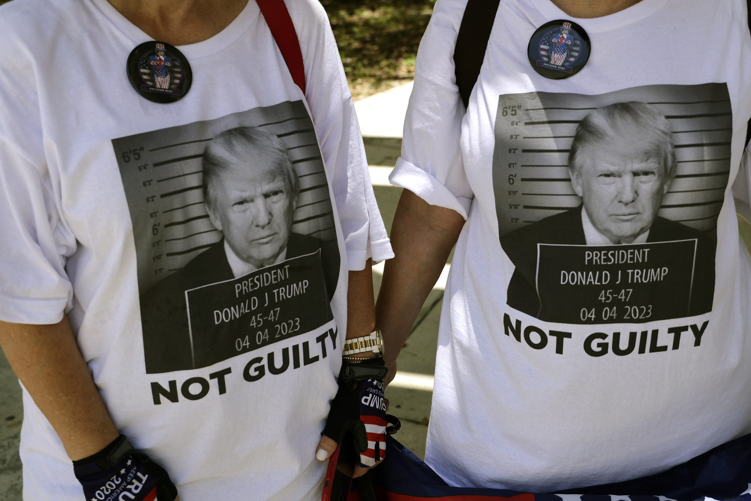 Two people wearing Trump shirts that say "Not guilty."