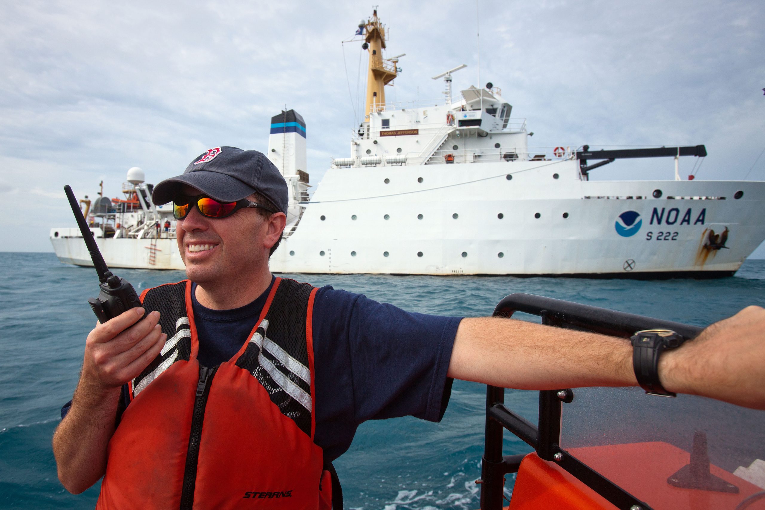 Captain Shepard Smith rides a launch as the the NOAA Ship Thomas Jefferson is seen in the background on the ocean.