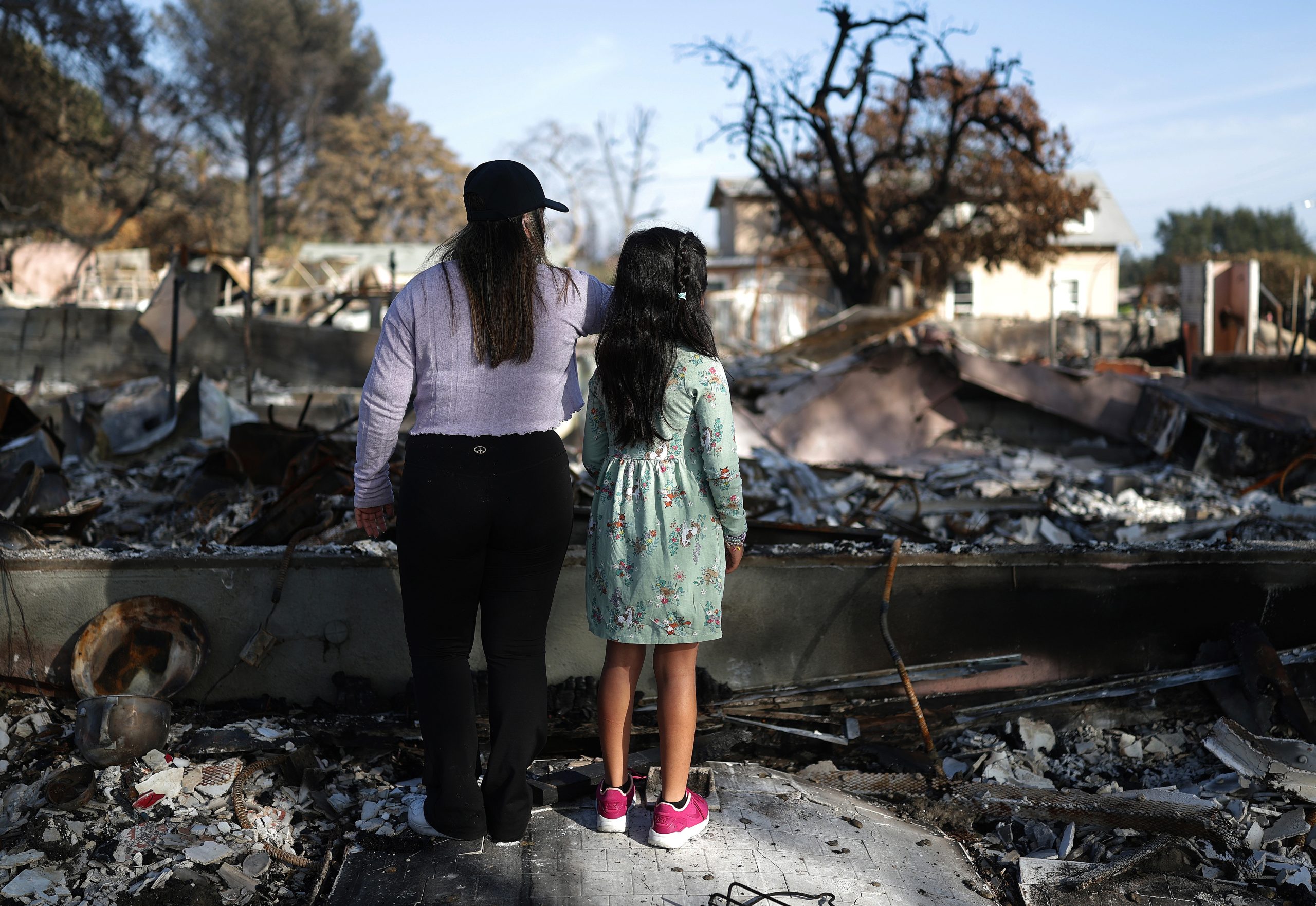 Sisters Lesly and Rose Garrido-Lopez view the remains of their home.