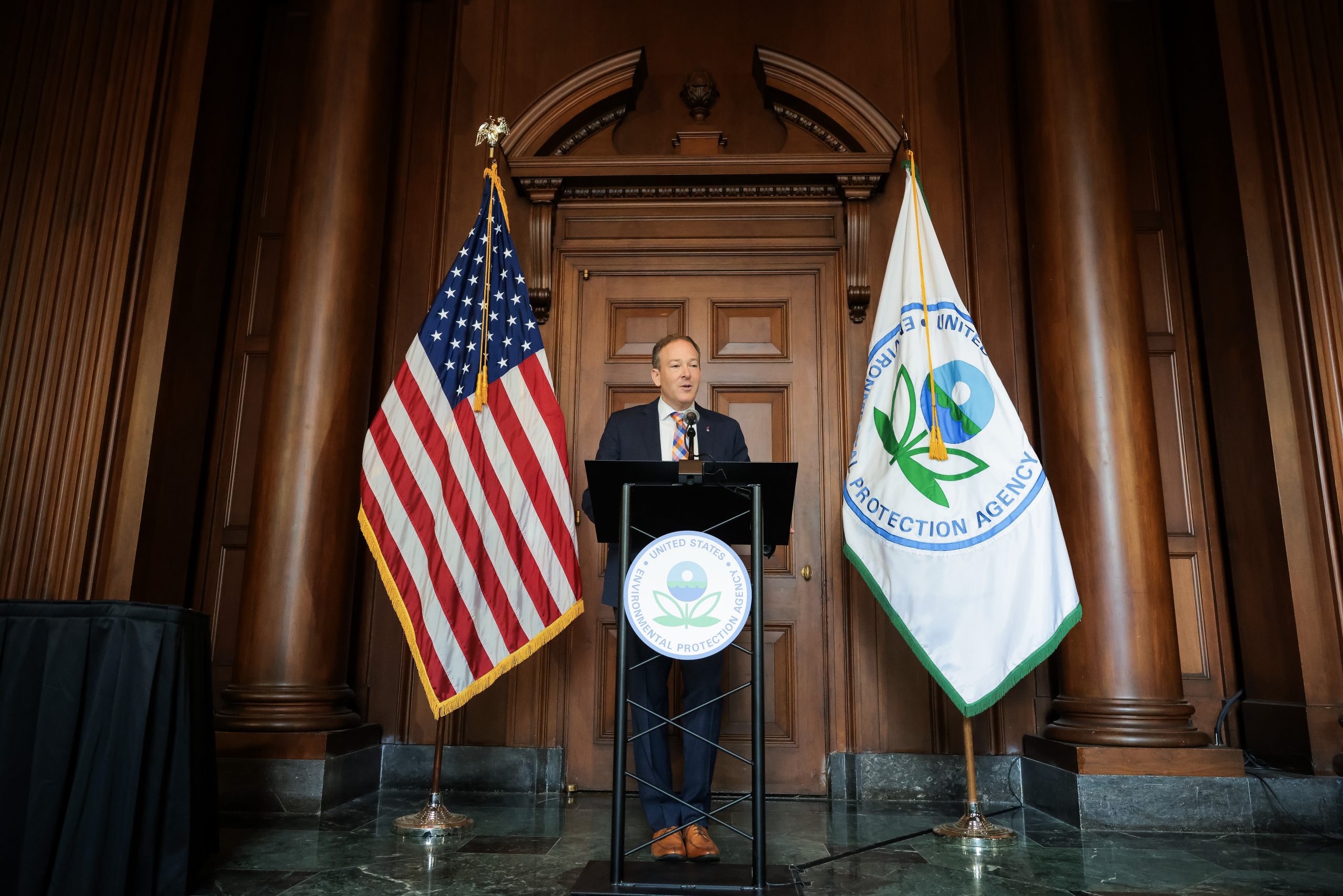 Lee Zeldin at a podium in between the American flag and the EPA flag.
