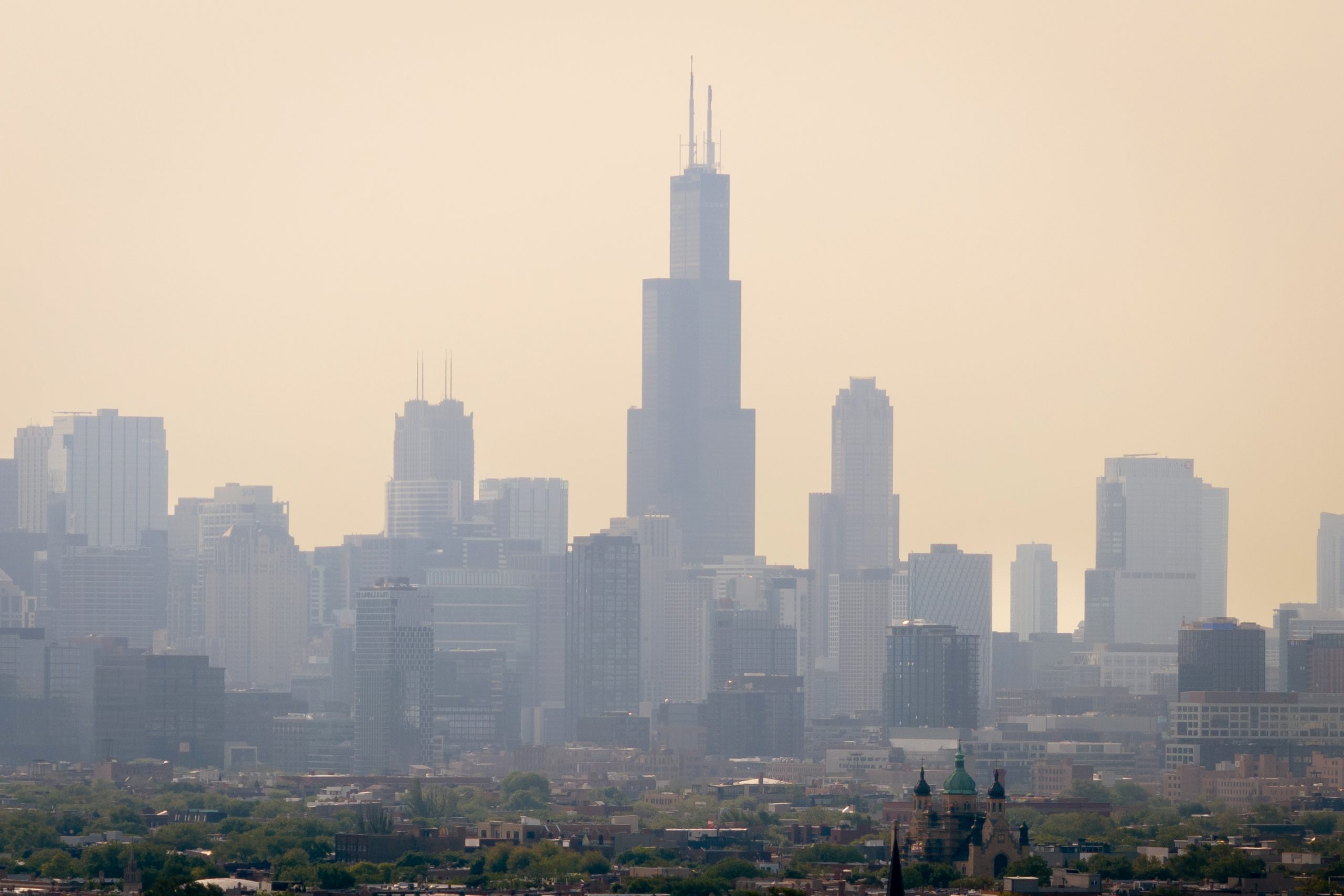 The Chicago skyline of skyscrapers, shrouded in an orange haze.