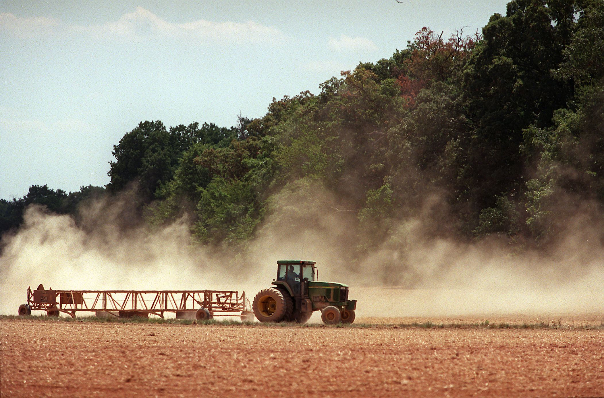 Dust rises as a farmer travels across his dry field.