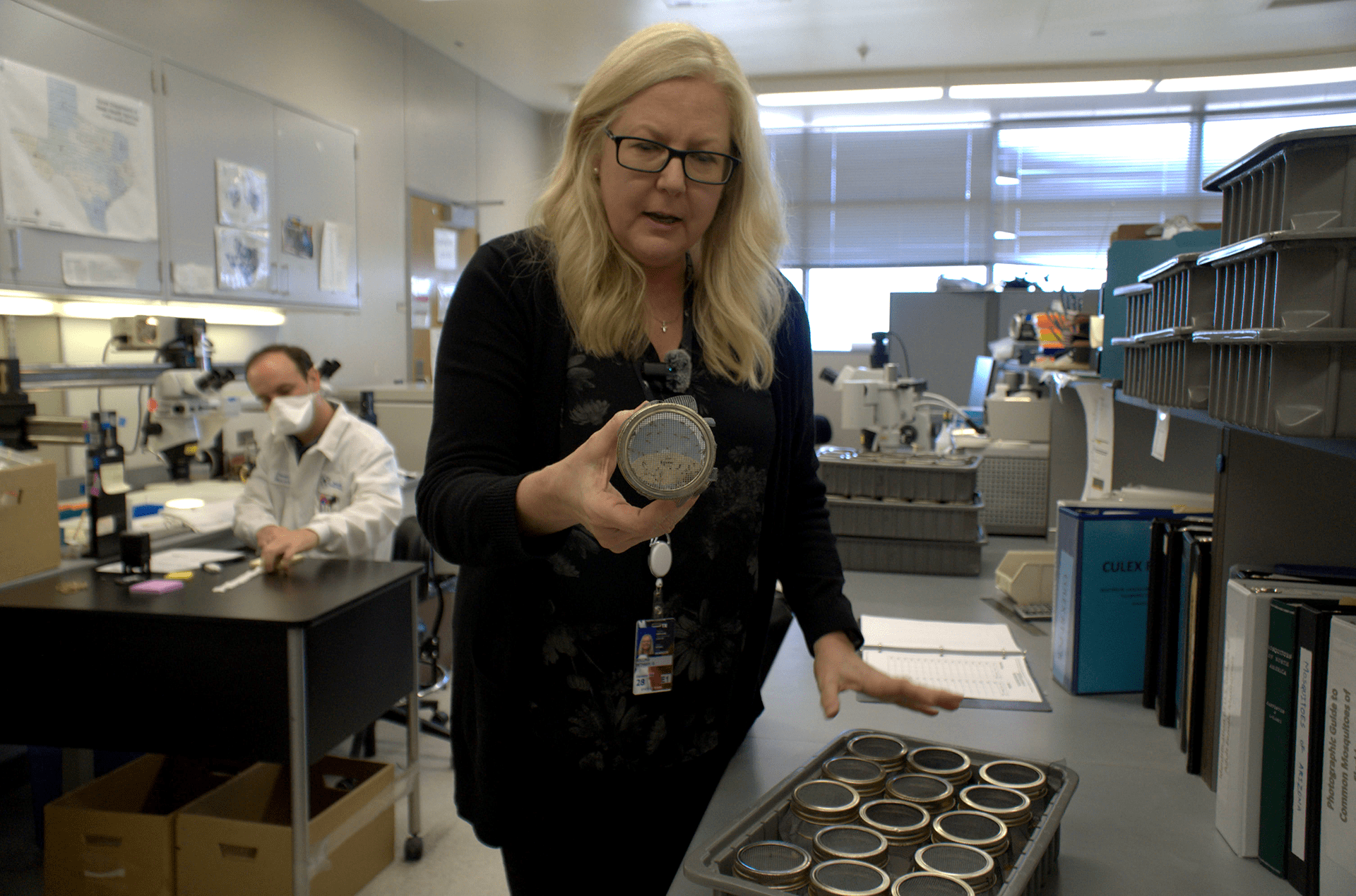 A woman holds a round container up to the camera. A woman holds a round container up to the camera.