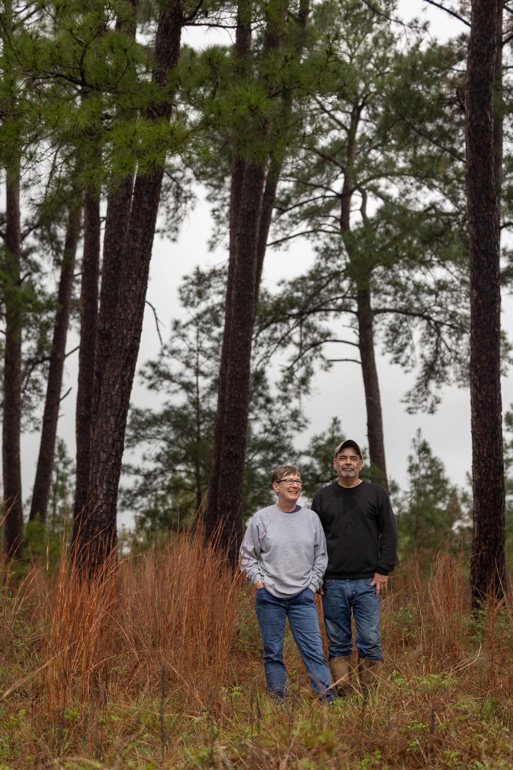 An older couple stand in a meadow on their property An older couple stand in a meadow on their property