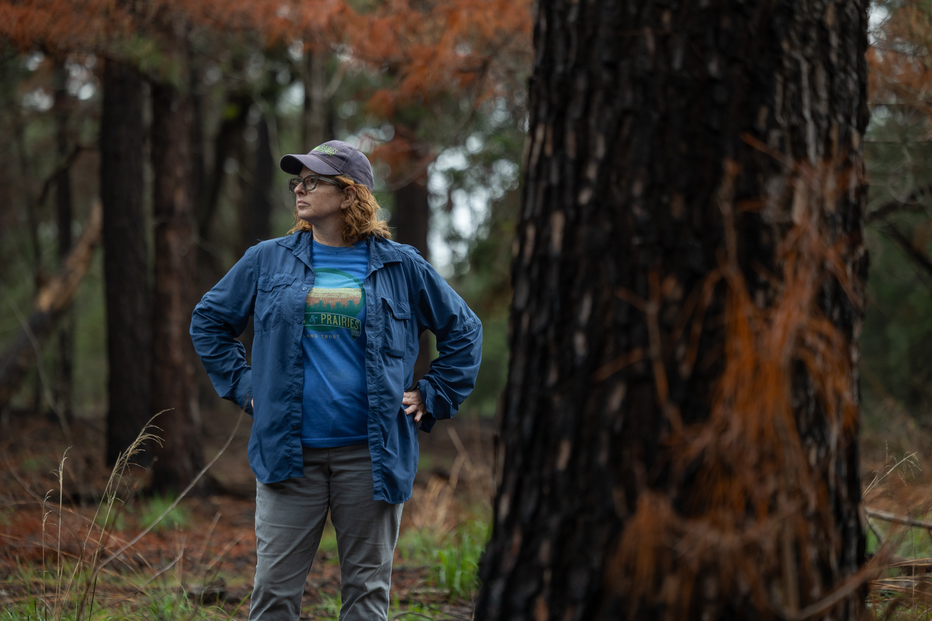 A woman standing in a wooded area with her hands on her hips, while looking off to the left. A woman standing in a wooded area with her hands on her hips, while looking off to the left.