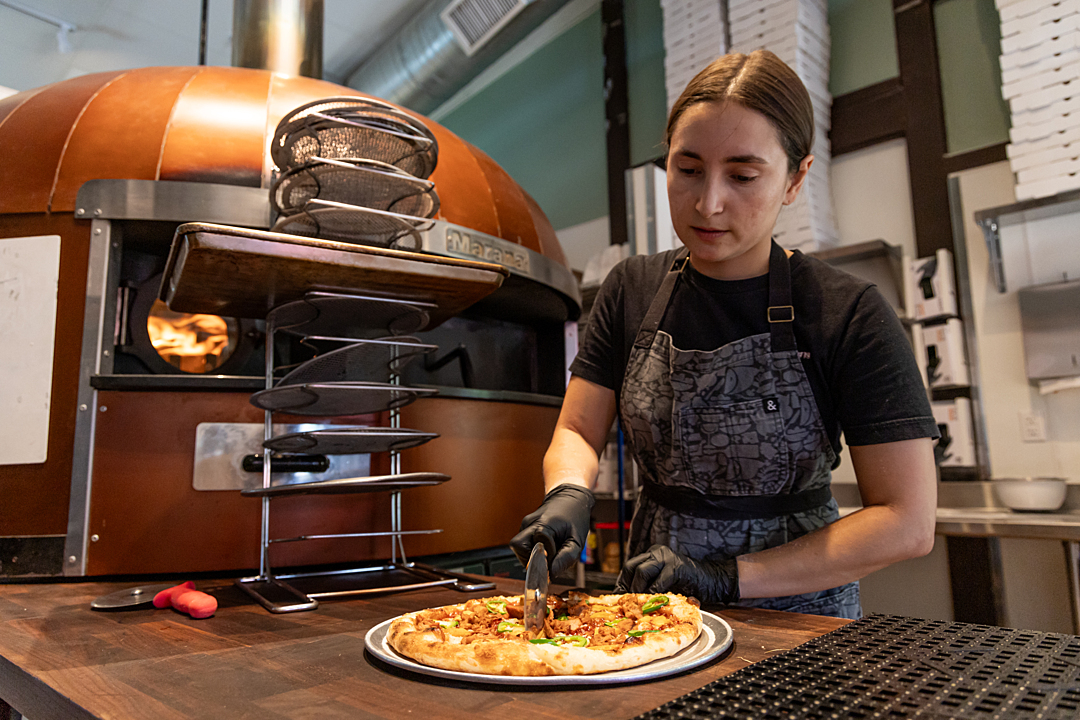 A sous-chef slicing into plant-based pizza A sous-chef slicing into plant-based pizza