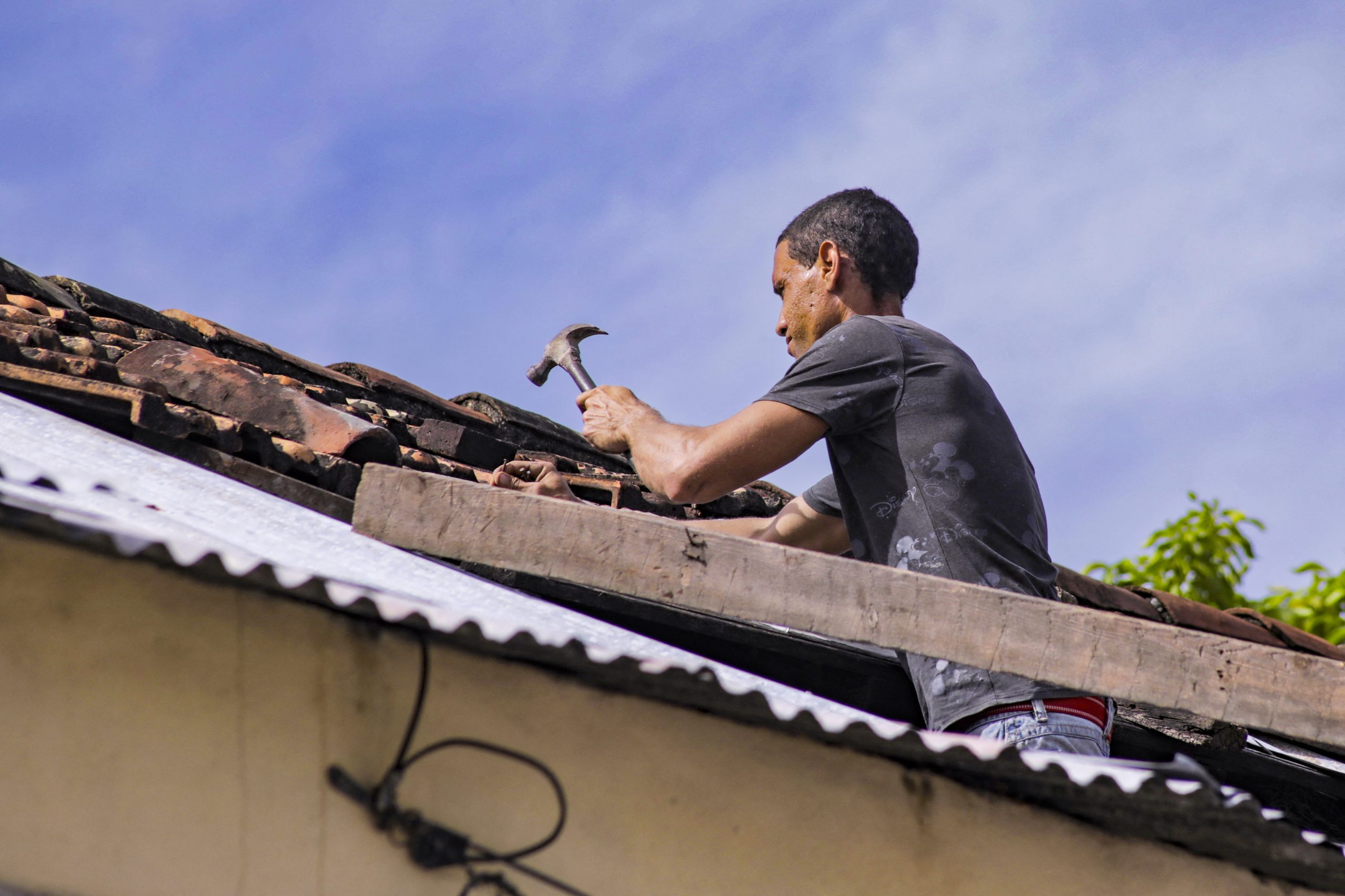 A man hammering a nail into a roof