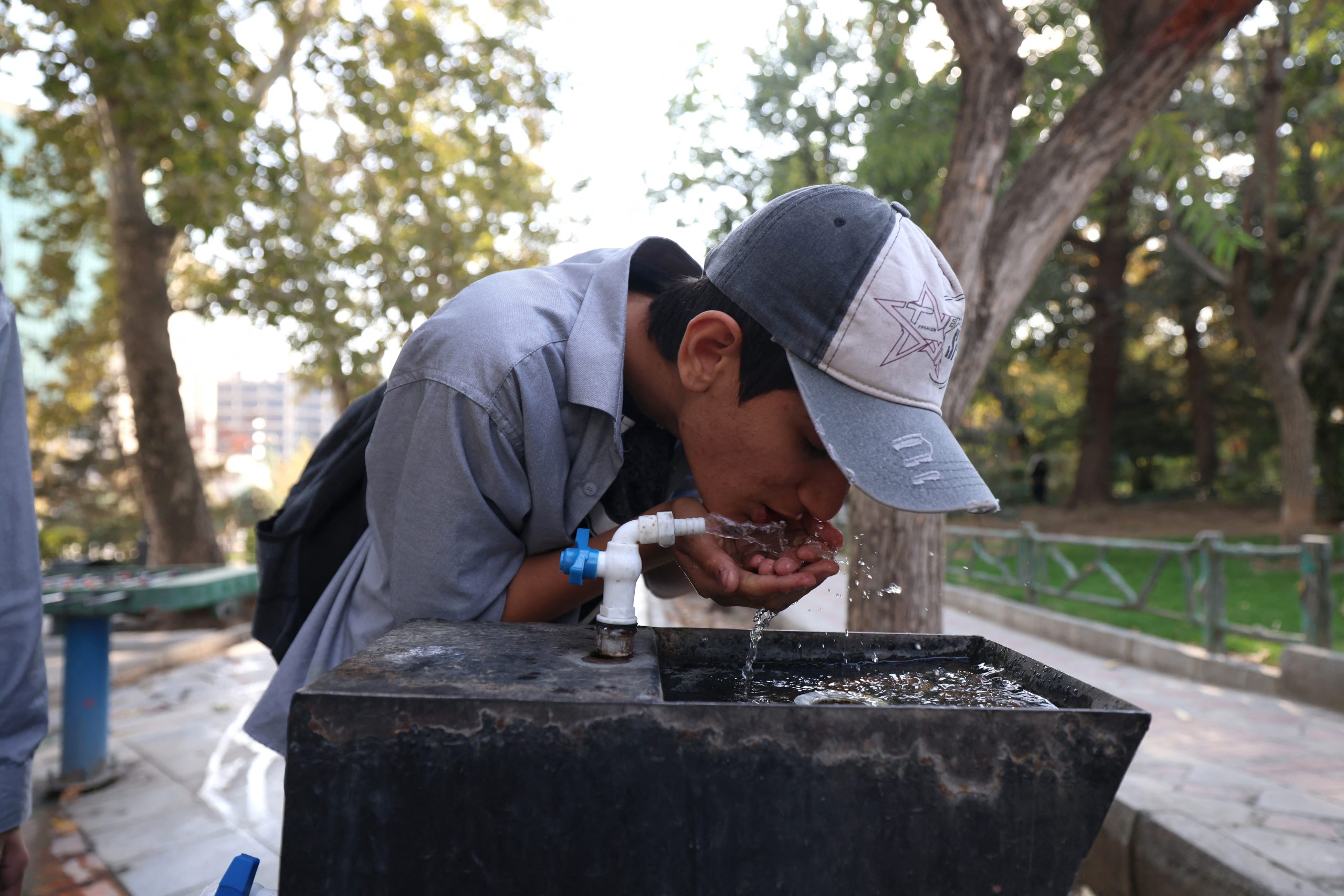 A young person drinks from a basin